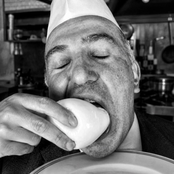 Un cuoco assaggia una mozzarella nella cucina del ristorante.