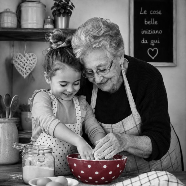 Una nonna e una bambina preparano insieme un impasto in cucina.